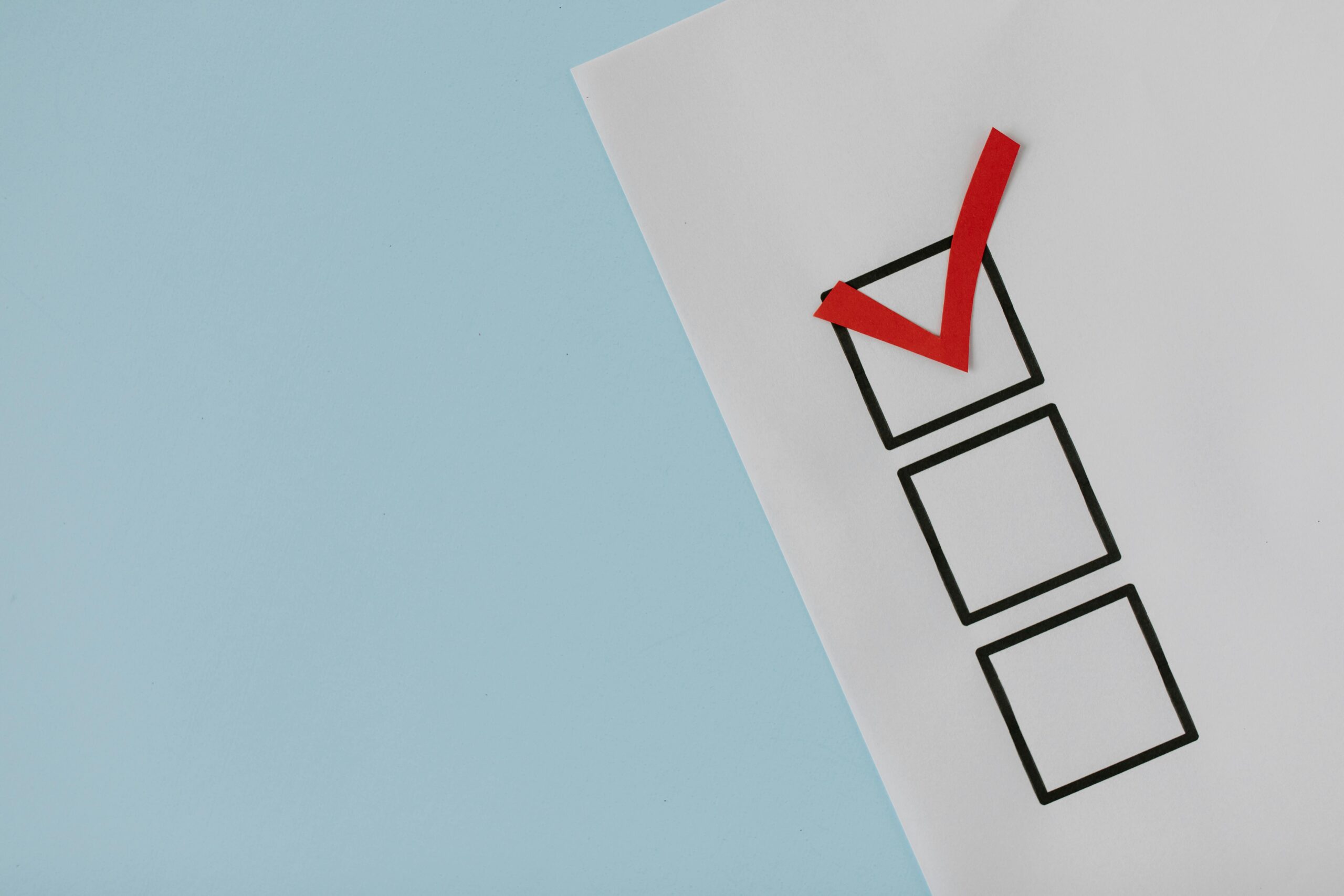 Checklist with a red check mark on paper against a blue background